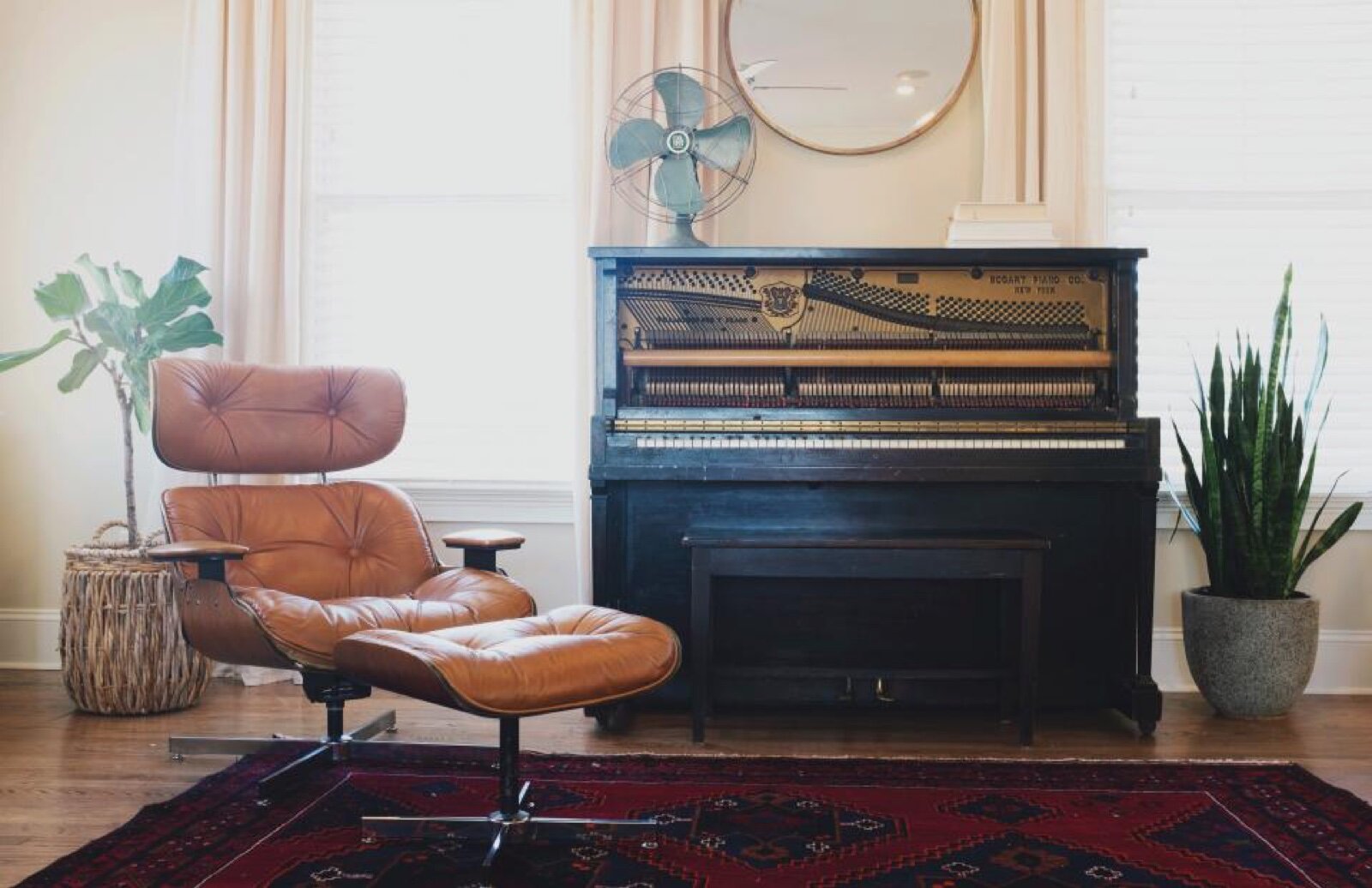 An upright piano with its top panel removed, standing against a wall in a domestic living room