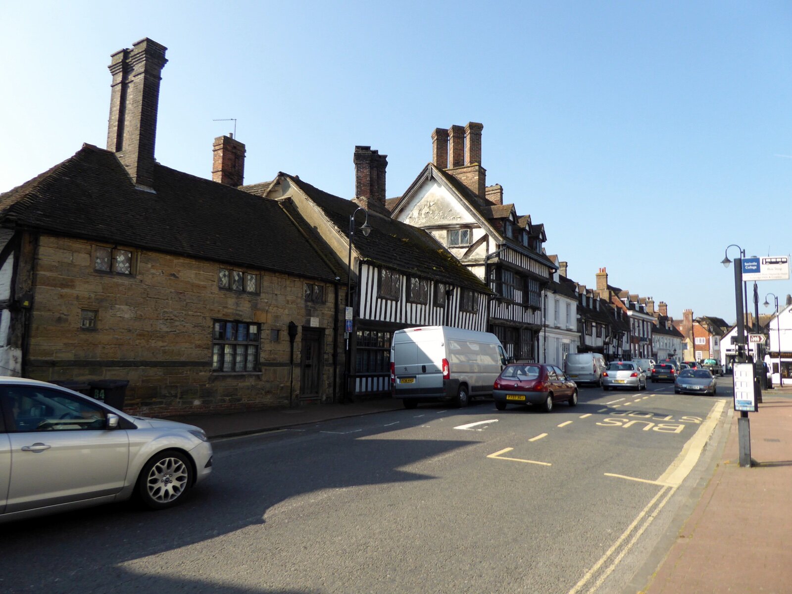 A row of old sandstone and black-and-white timber-framed buildings with tall brick chimneys along East Grinstead High Street