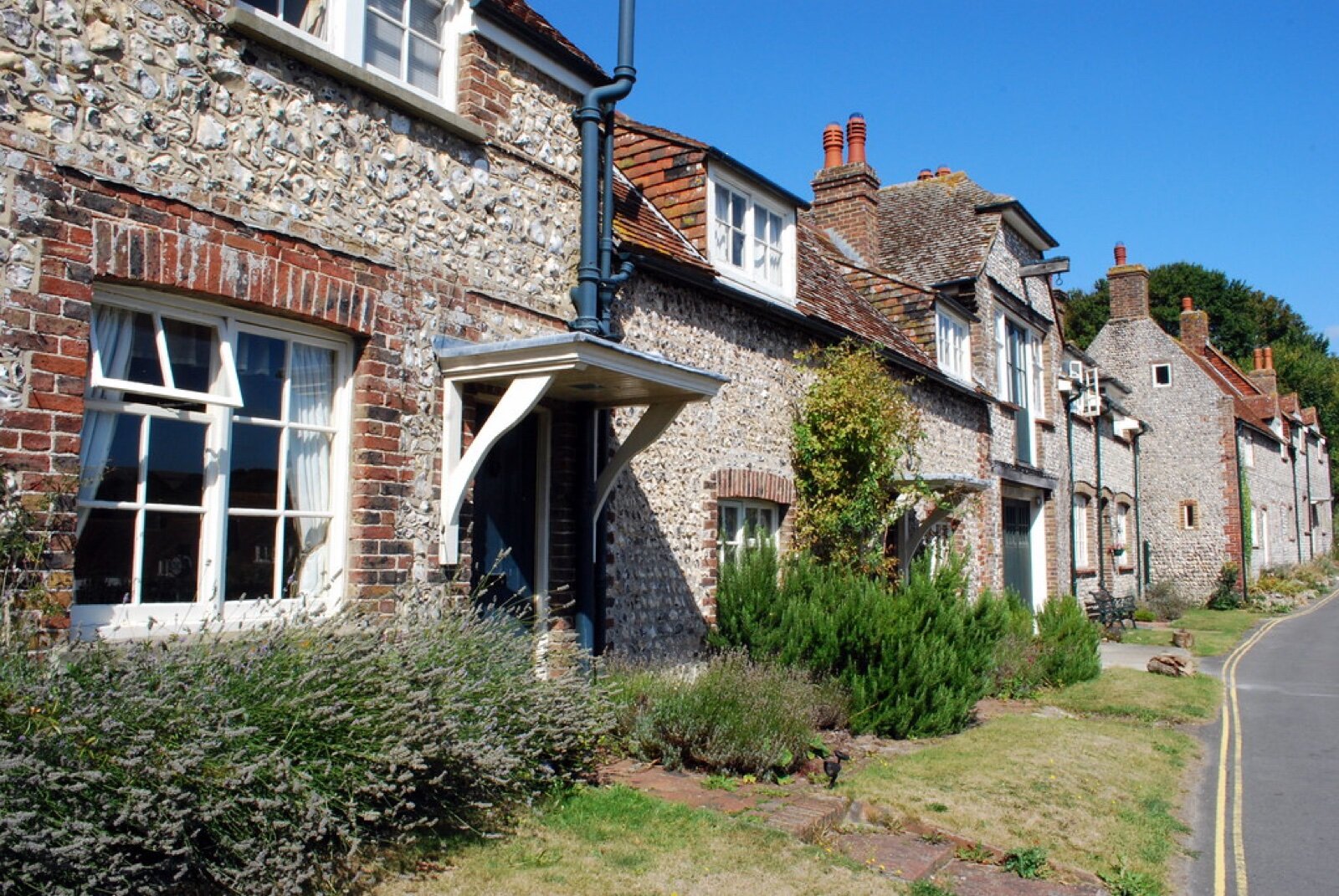 A terrace of flint and brick cottages on a village street below the South Downs