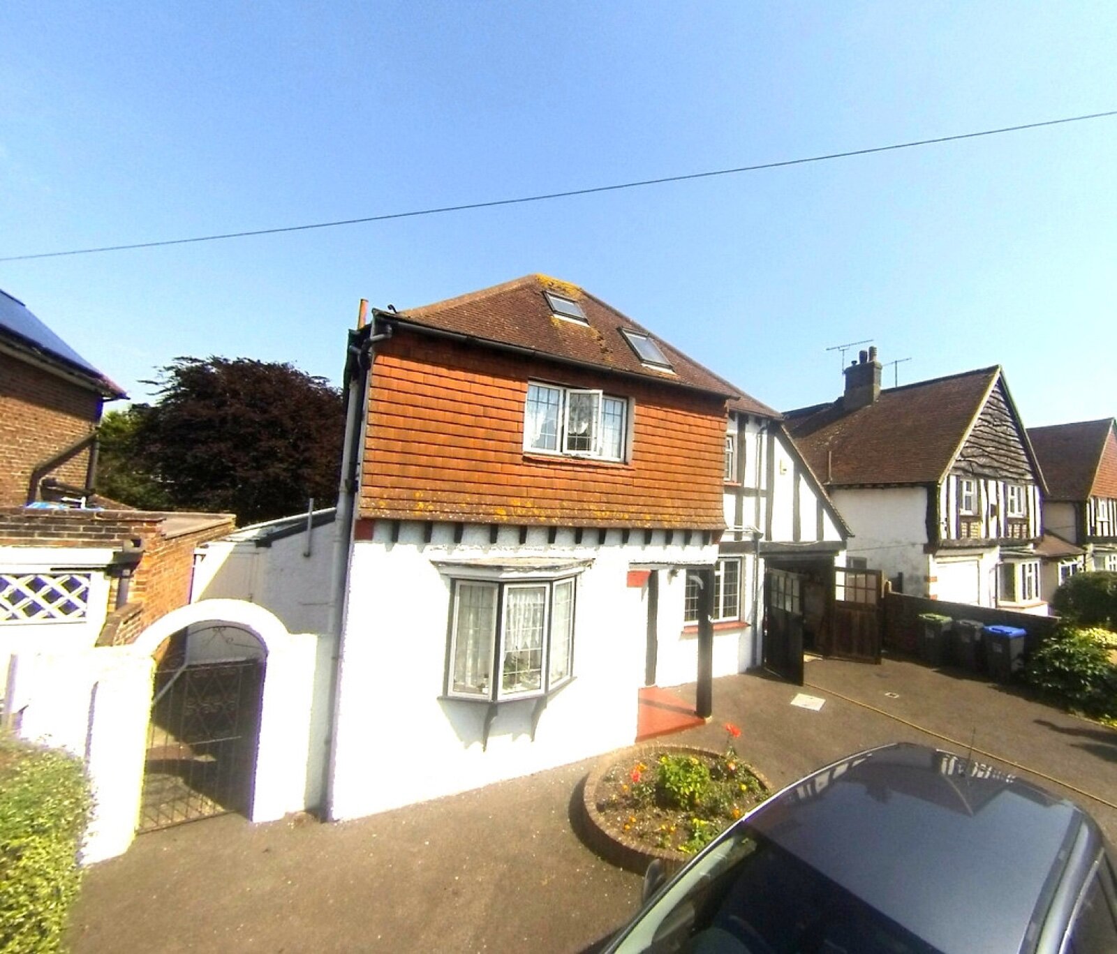 A detached Worthing house with a tile-hung upper storey, bay window and mock-Tudor neighbours