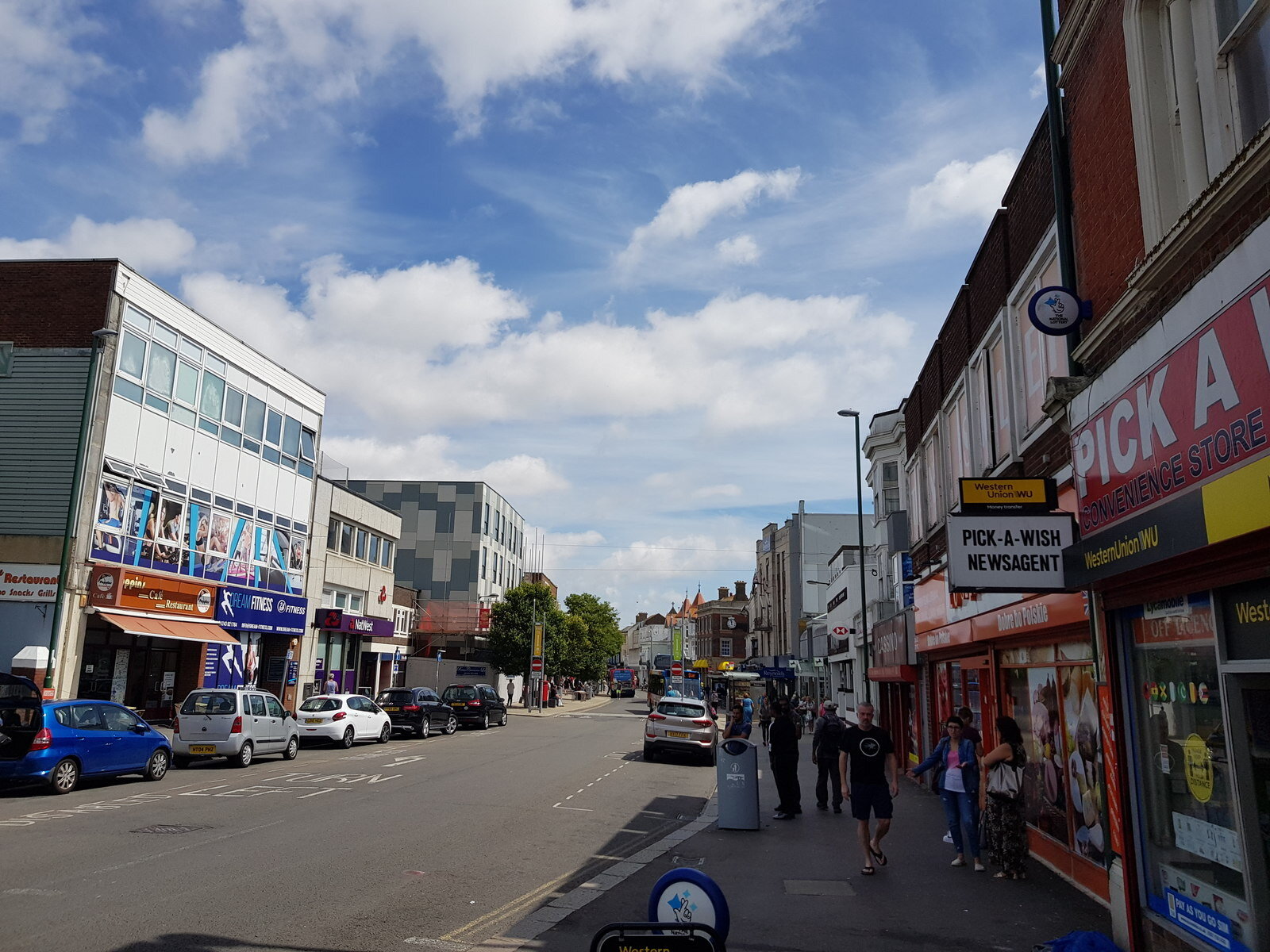 Bognor Regis High Street looking east, with parked cars along the kerb and shopfronts either side