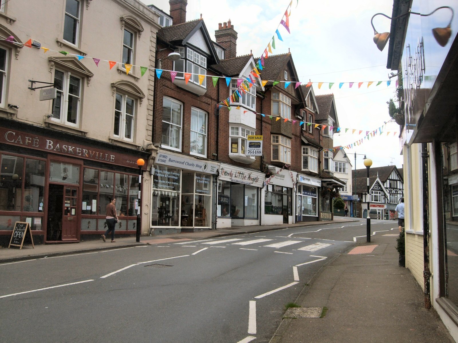 Crowborough High Street with Cafe Baskerville, a row of shops under bunting and a zebra crossing