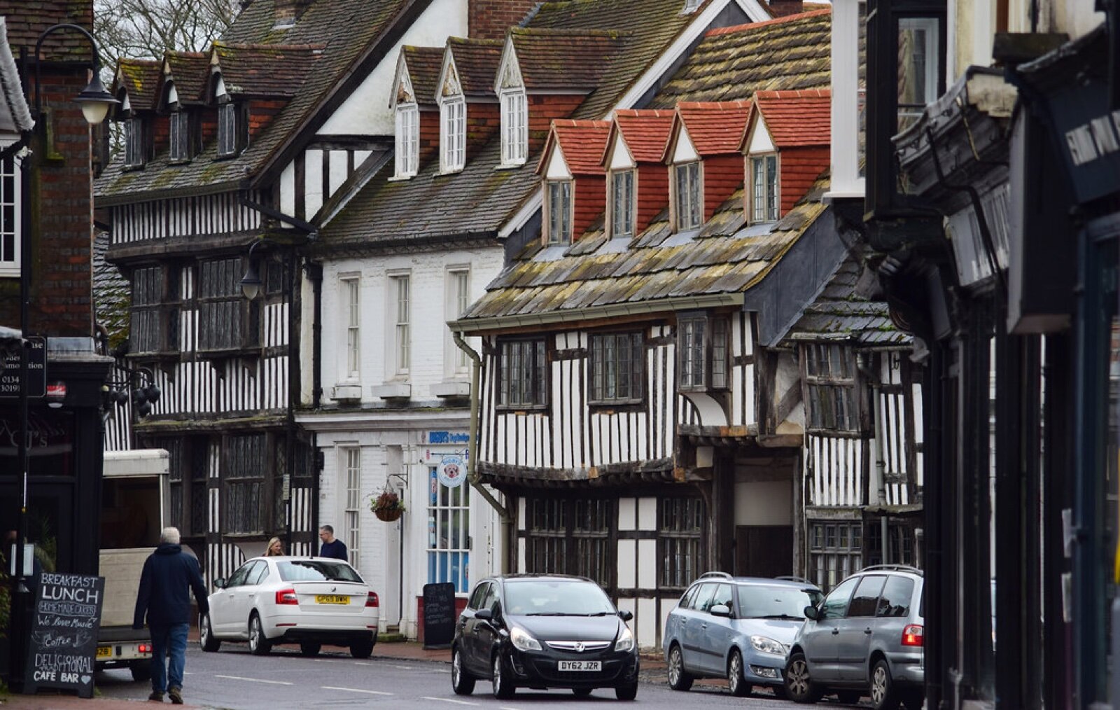 Timber-framed buildings on East Grinstead High Street with cars parked along the kerb