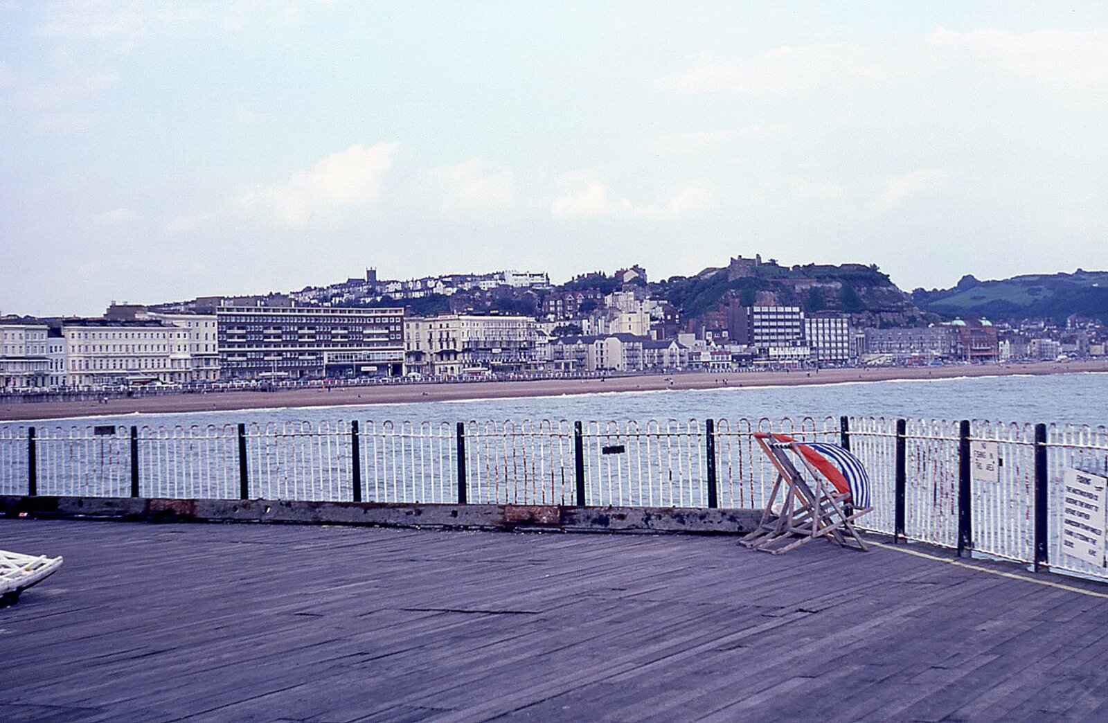 Hastings seafront seen from the pier, with terraced buildings along the front and the castle on the hill above the Old Town