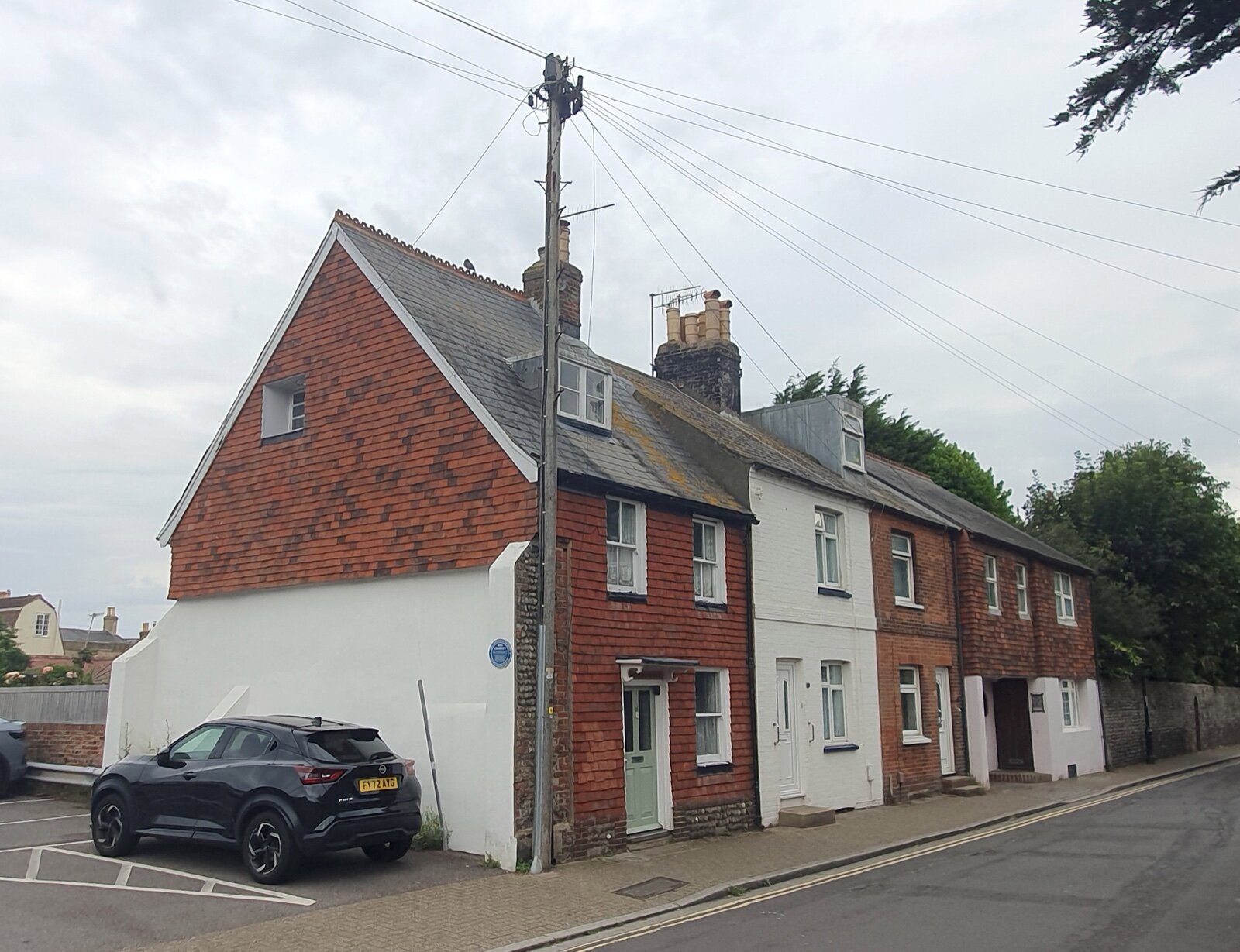A row of brick and white-painted terraced houses on Middle Street in Shoreham-by-Sea, with a car parked on the corner